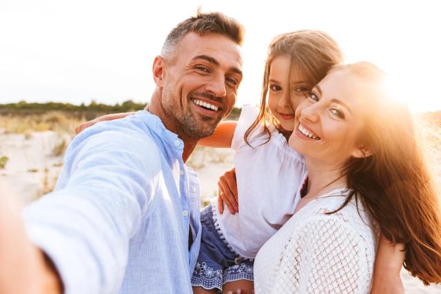 a happy family is taking a selfie on the beach .