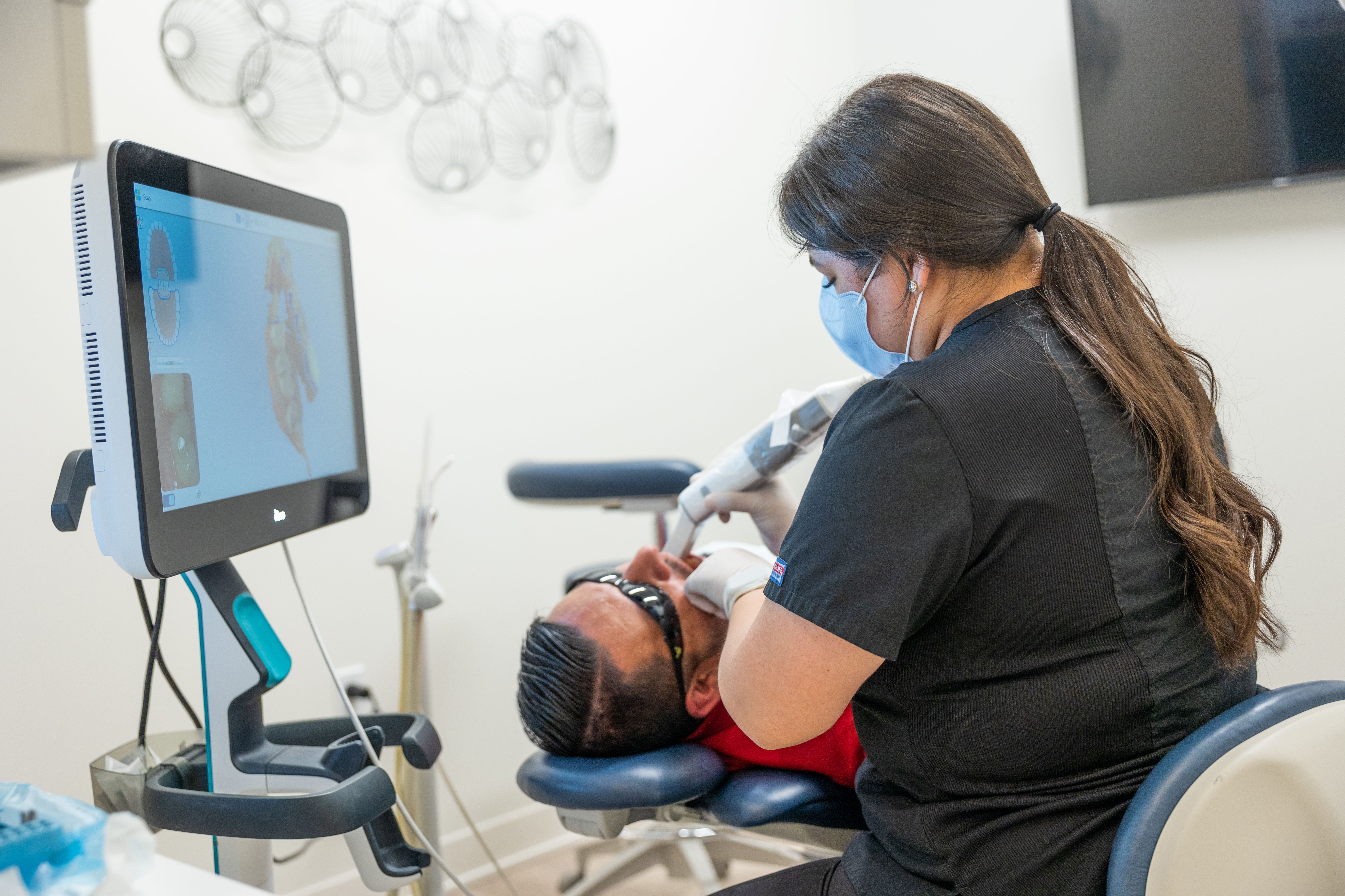 a female dentist is examining a man 's teeth in a dental office .