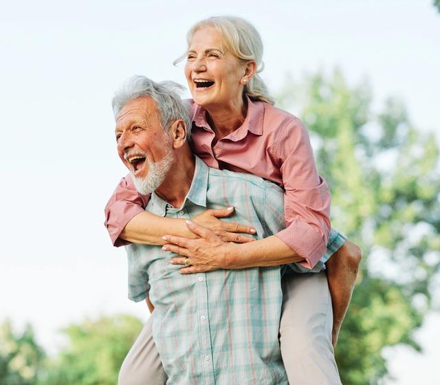 a man is carrying a woman on his back in a park .