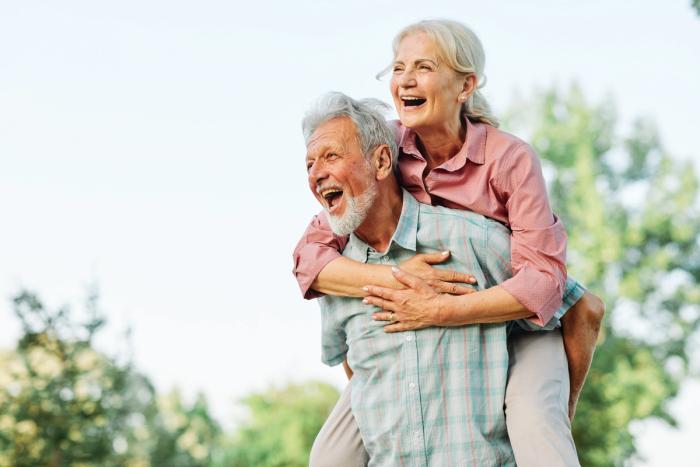 a man is carrying a woman on his back in a park .