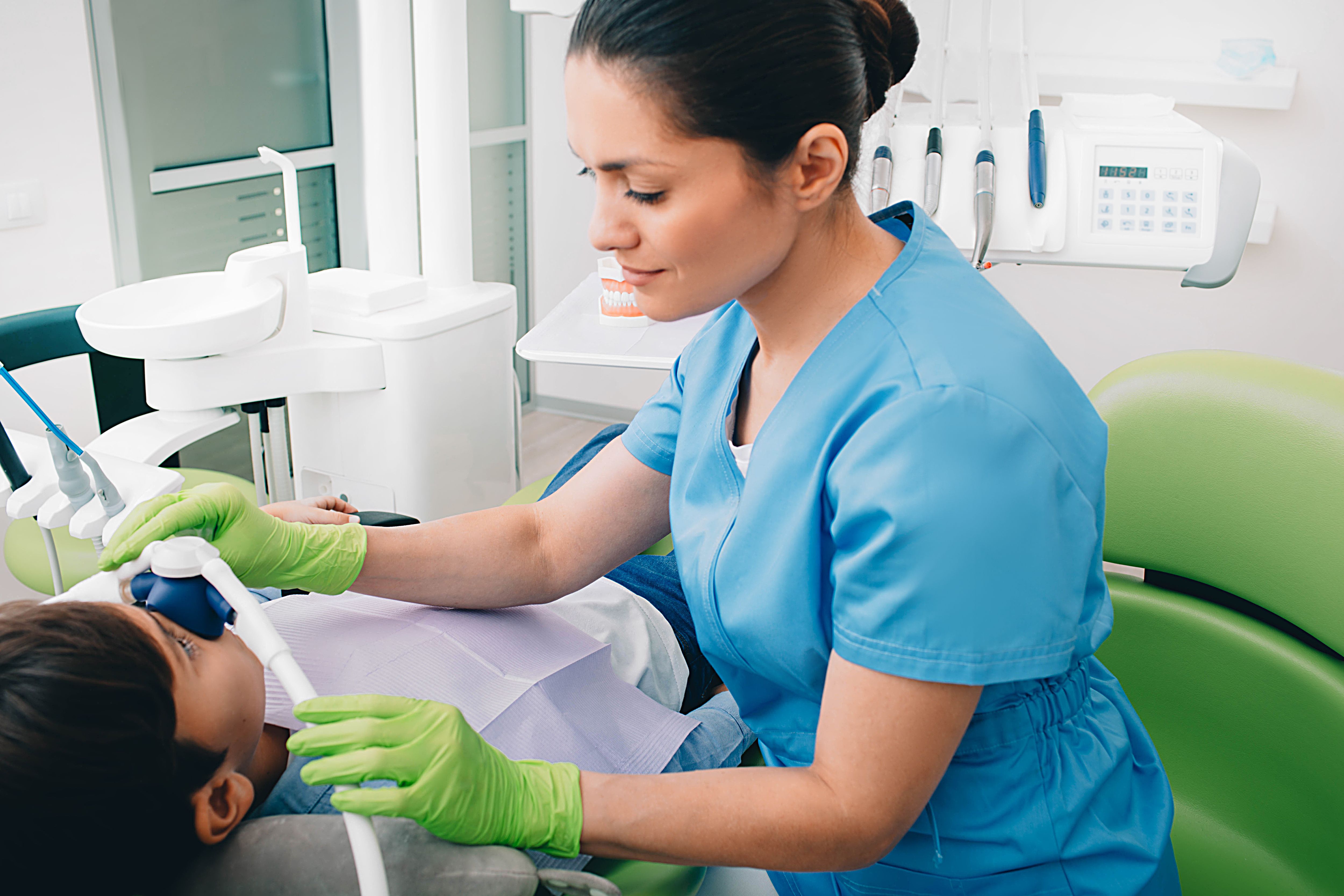 a female dentist is examining a young boy 's teeth in a dental office .