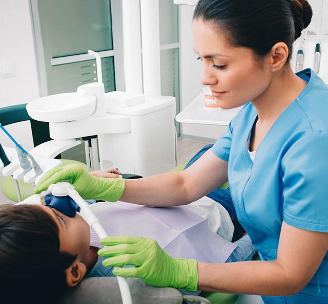 a female dentist is examining a young boy 's teeth in a dental office .