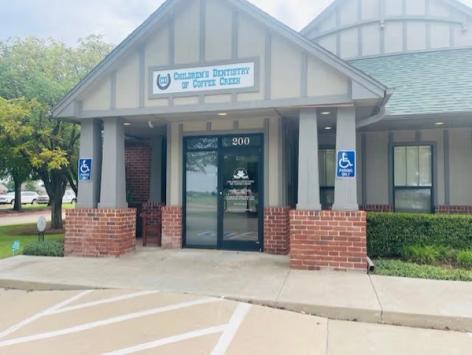 Exterior of "Children's Dentistry of Coffee Creek" office with brick pillars and accessible parking signs.