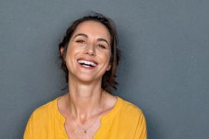 a woman in a yellow shirt is smiling and looking at the camera .