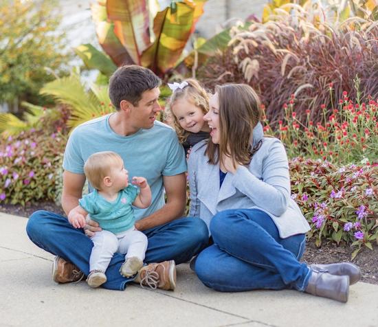 a family is sitting on the sidewalk with a baby .