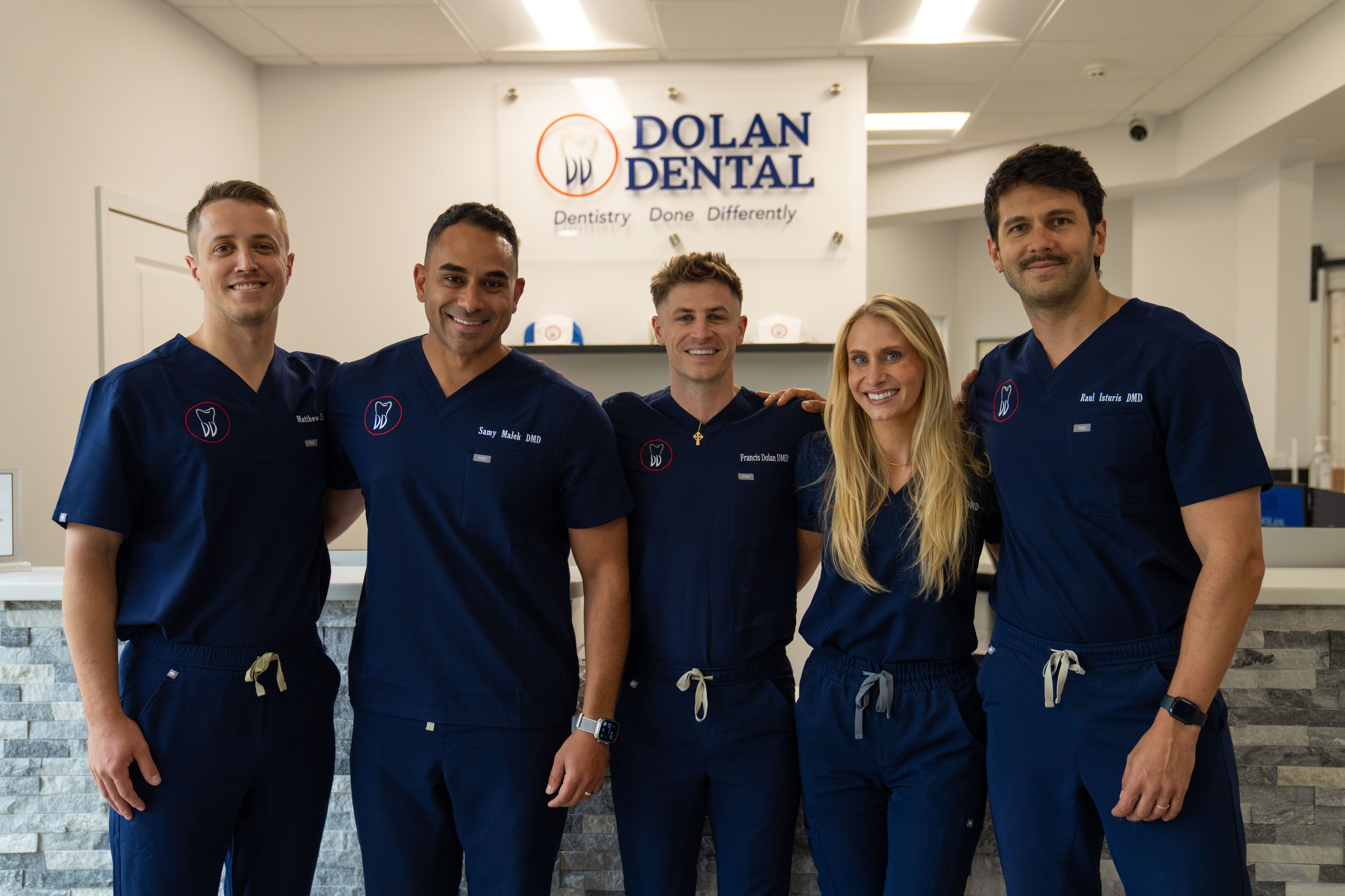 a man in a scrub is smiling in front of a dental sign .