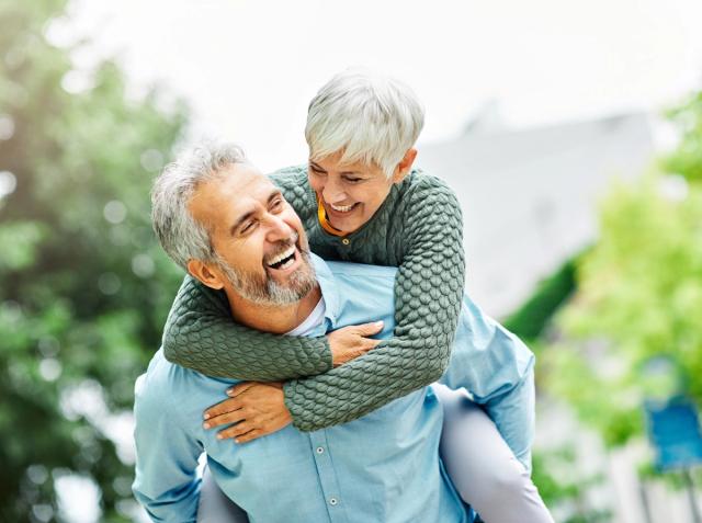 a man is carrying a woman on his back and they are laughing .