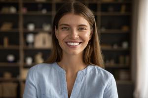 Smiling young woman with brown hair in a light blue shirt.