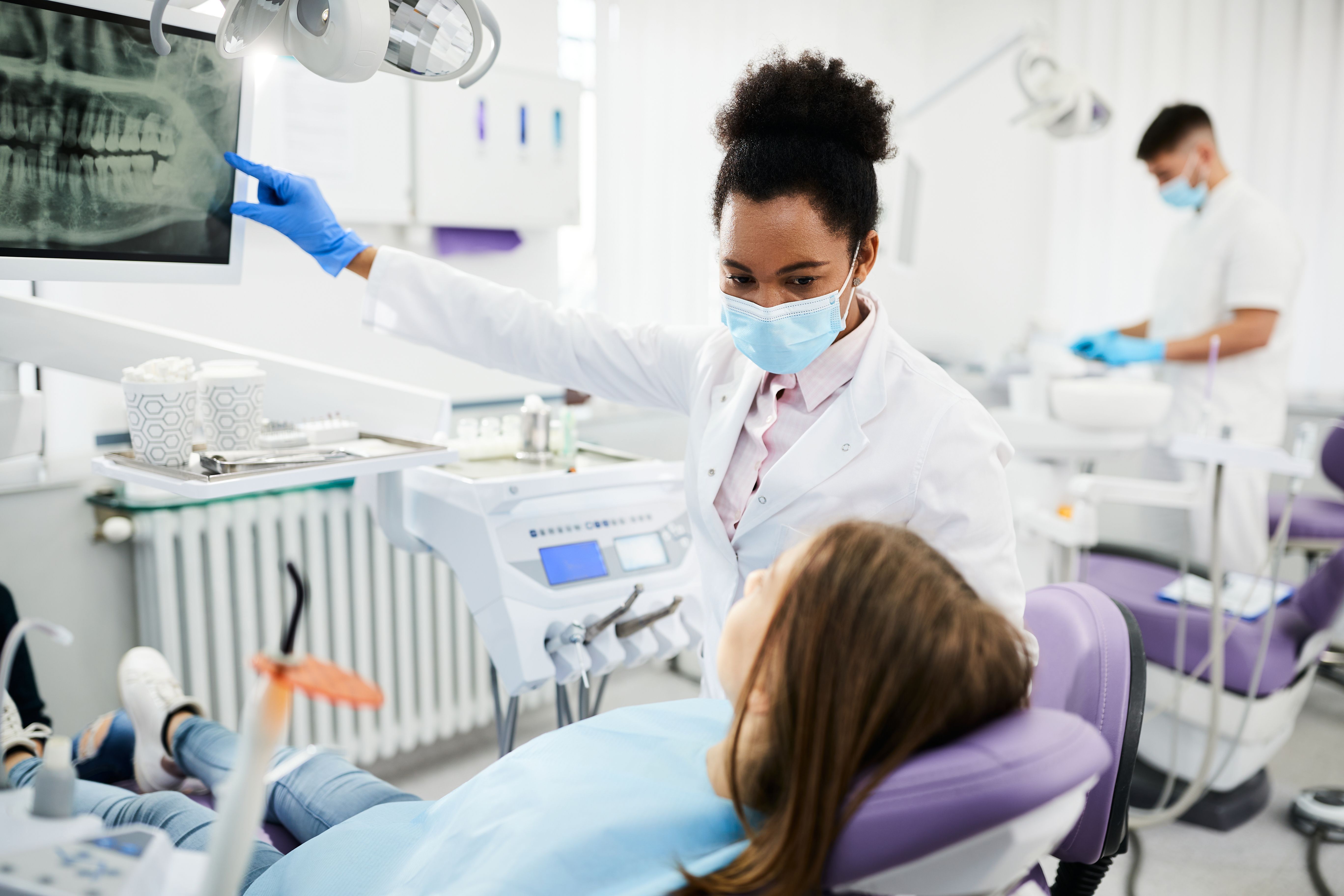 a female dentist is looking at an x-ray of a patient 's teeth in a dental office .