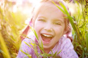 a little girl is laying in the grass and laughing.