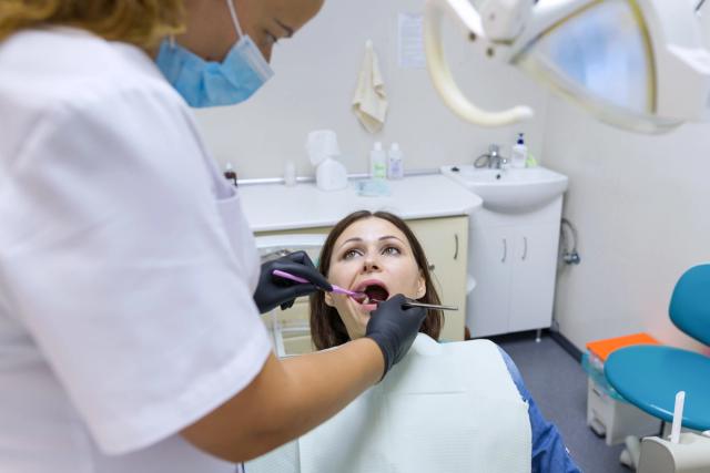 a woman is getting her teeth examined by a dentist in a dental office .