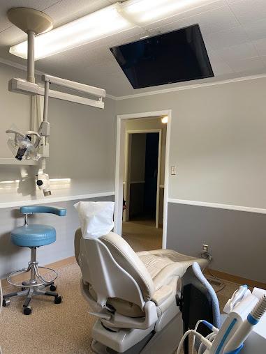 a dental office with a dental chair and a television on the ceiling .