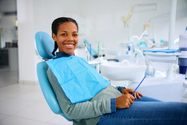 a woman is sitting in a dental chair and smiling .