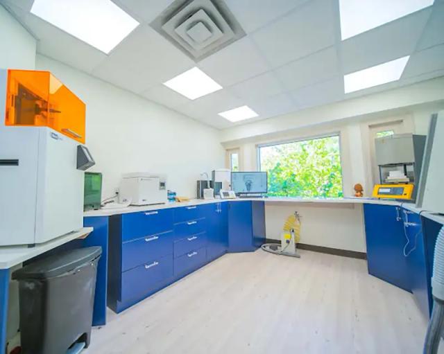 a dental lab with blue cabinets and a large window .
