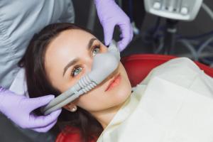 a woman is laying in a dental chair with an oxygen mask on her face.