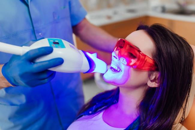 a woman is getting her teeth whitened by a dentist .
