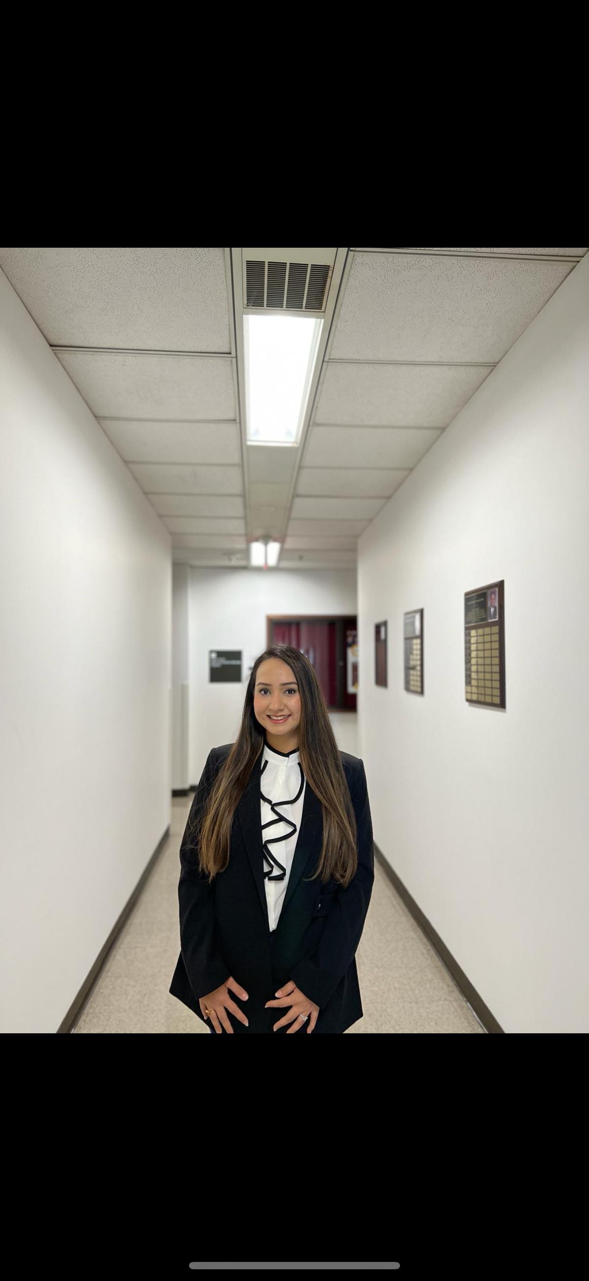 a woman in a suit is standing in a hallway with her hands on her hips .