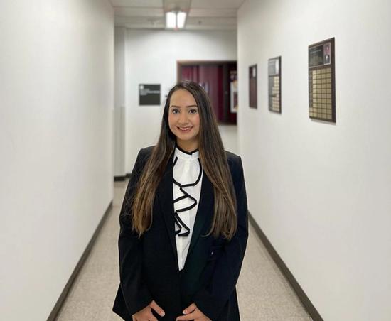 a woman in a suit is standing in a hallway with her hands on her hips .