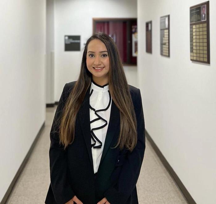 a woman in a suit is standing in a hallway with her hands on her hips .
