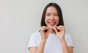 a woman is holding a clear brace in her hands and smiling .