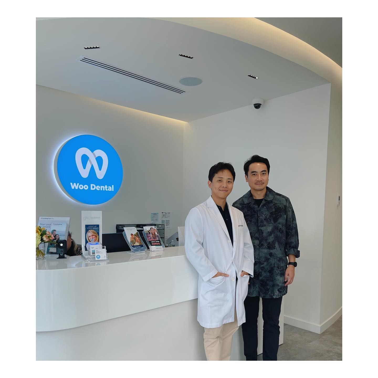 two men in white coats are standing in front of a dental office .