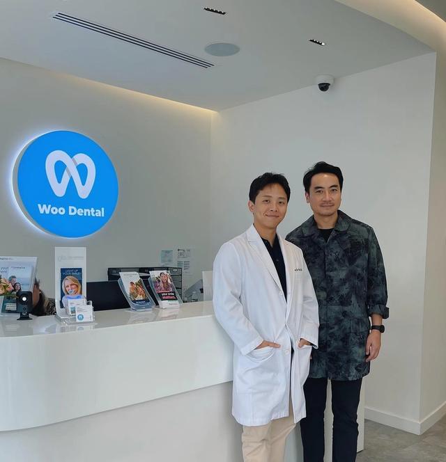 two men in white coats are standing in front of a dental office .