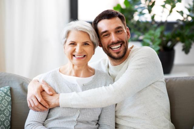 a young man is hugging an older woman on a couch .