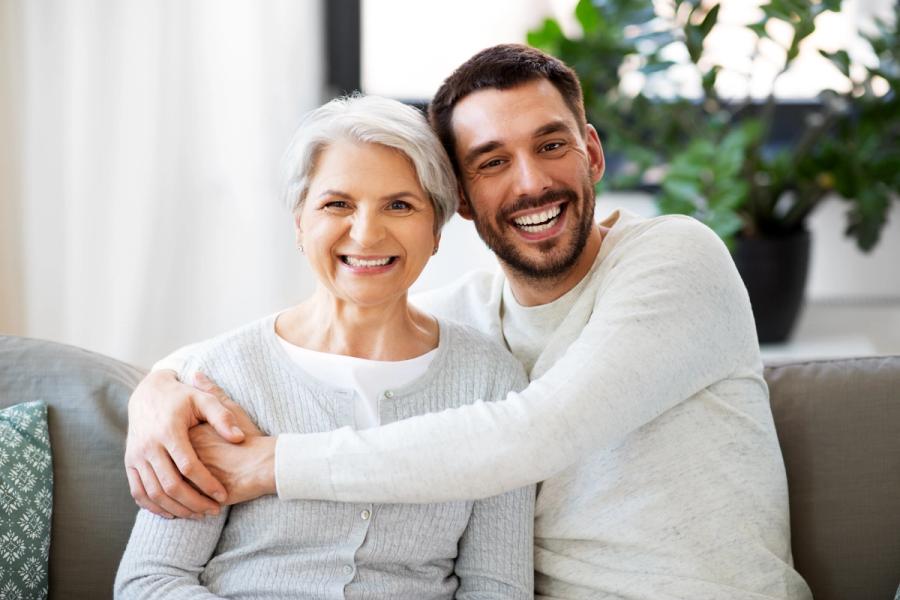 a young man is hugging an older woman on a couch .