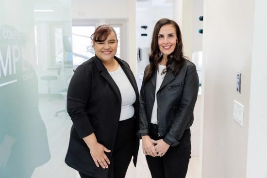 two women are standing next to each other in a dental office .