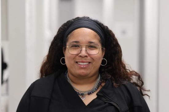 a woman wearing glasses and a necklace is smiling for the camera .