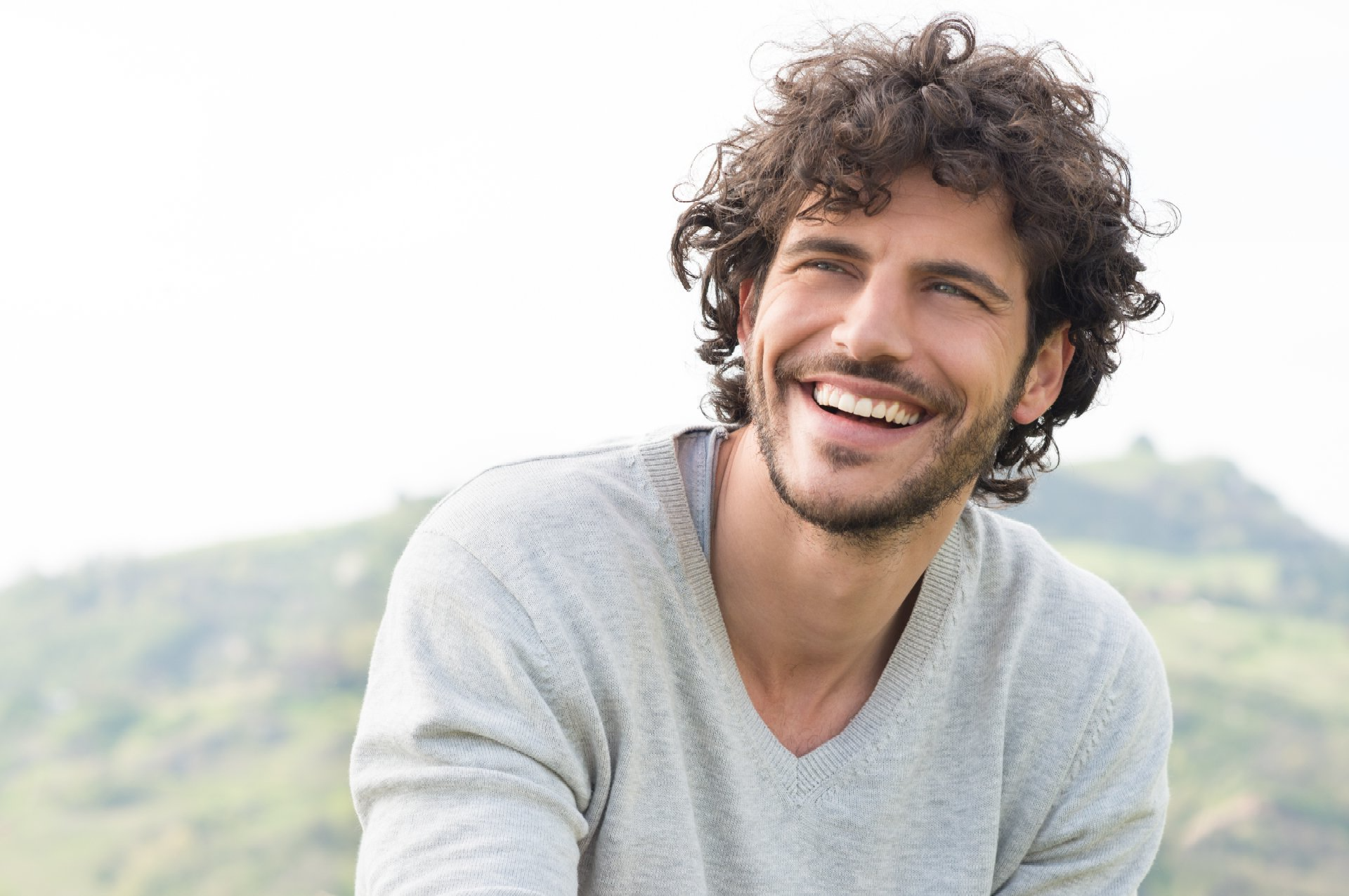 a man with curly hair and a beard is smiling
