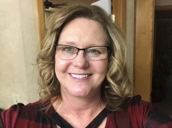 a woman wearing glasses and a plaid shirt is smiling for the camera .