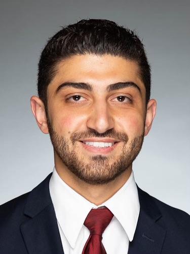 a man with a beard is wearing a suit and tie and smiling for the camera .