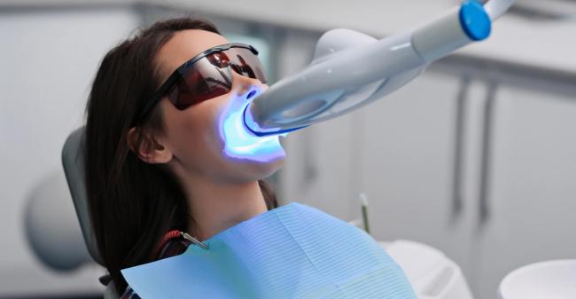 a woman is getting her teeth whitened at the dentist .