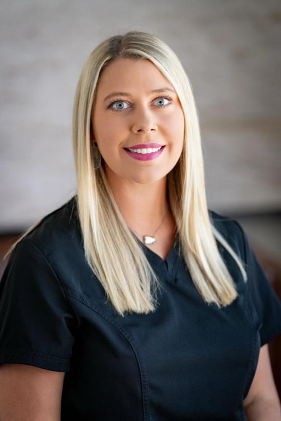 a woman in a black scrub top is smiling for the camera .