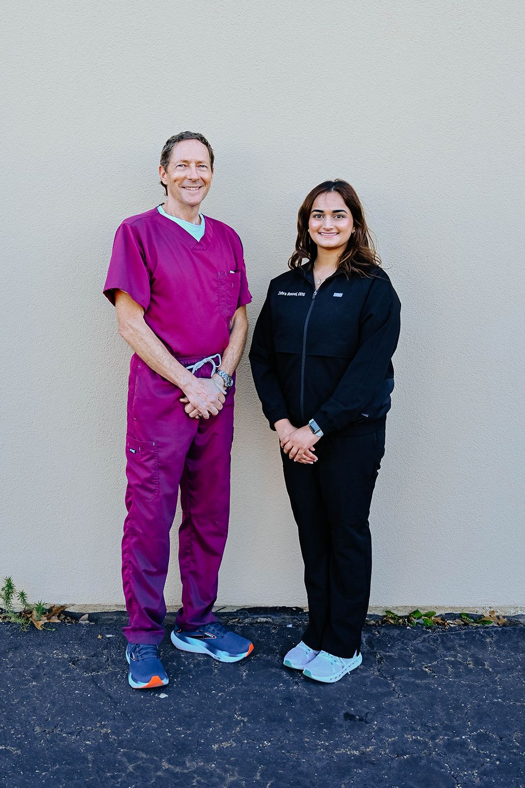 a man and a woman standing next to each other with the man wearing a pink scrub top