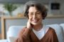 an elderly woman wearing glasses is smiling while sitting on a couch