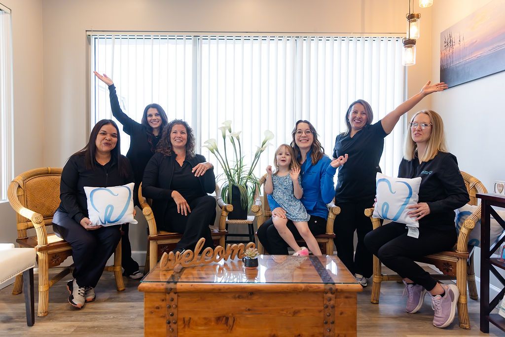 a group of women and a little girl are posing for a picture in a dental office .