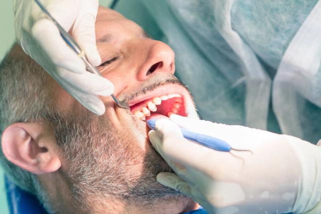 a man is getting his teeth examined by a dentist .