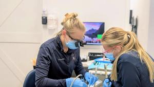 two female dentists are working on a patient 's teeth in a dental office .
