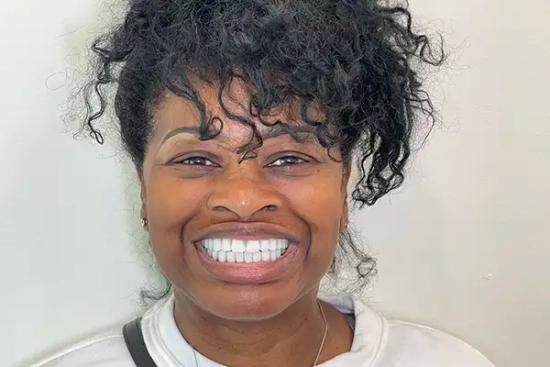 a woman with curly hair is smiling with her teeth showing .