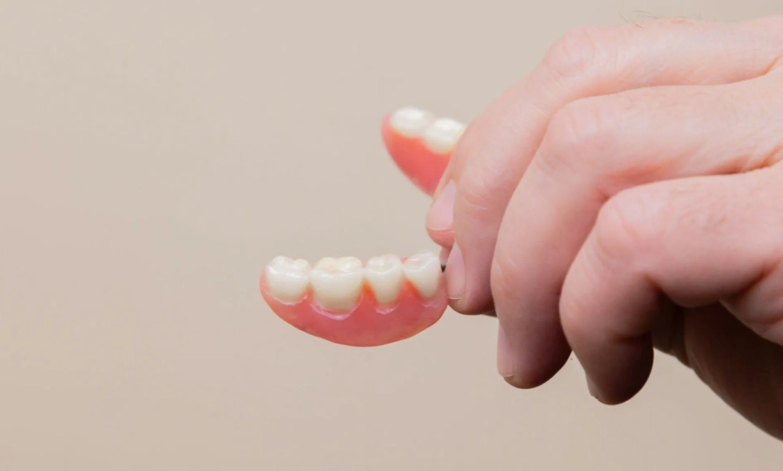 a person is holding a denture in their hand
