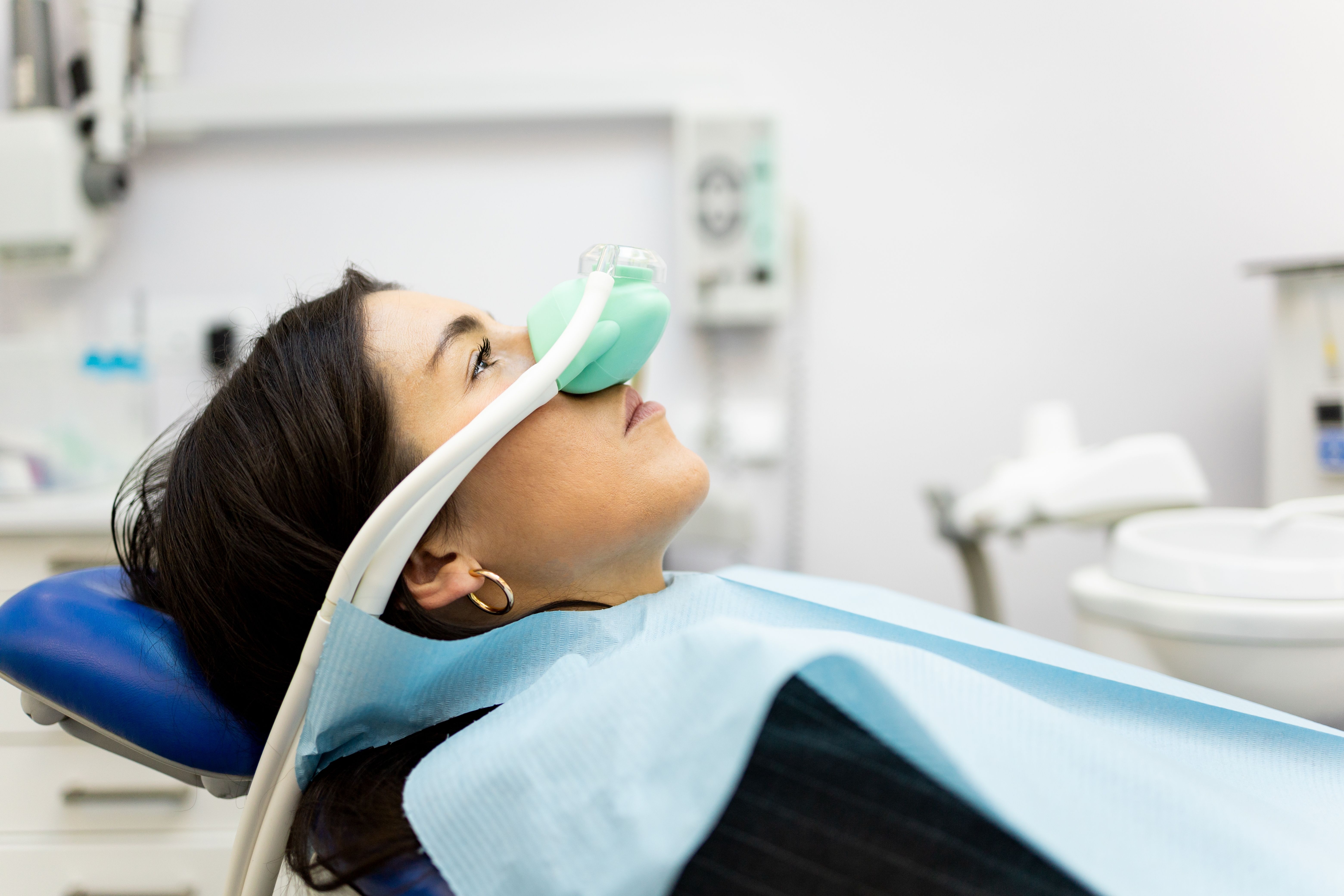 a woman is laying in a dental chair with an oxygen mask on her face .