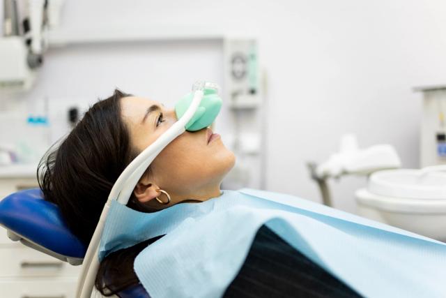 a woman is laying in a dental chair with an oxygen mask on her face .