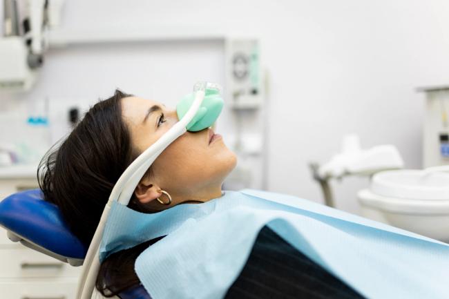 Woman in a dental chair with a green sedation mask.
