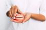a woman is holding a denture in her hands .