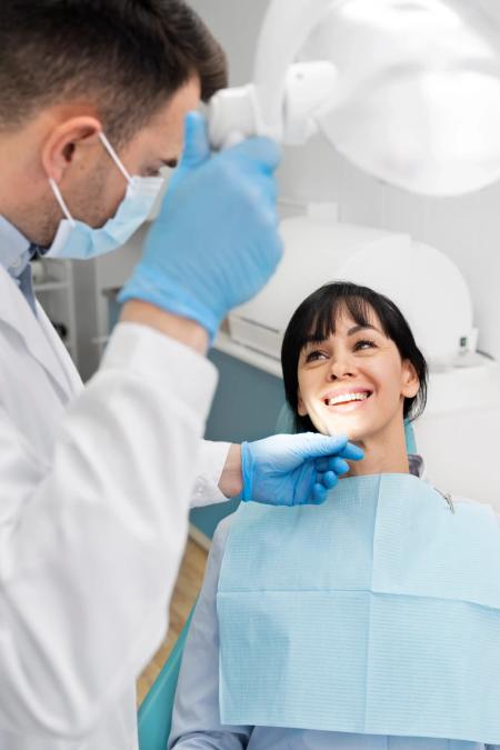 a woman is sitting in a dental chair while a dentist examines her teeth .