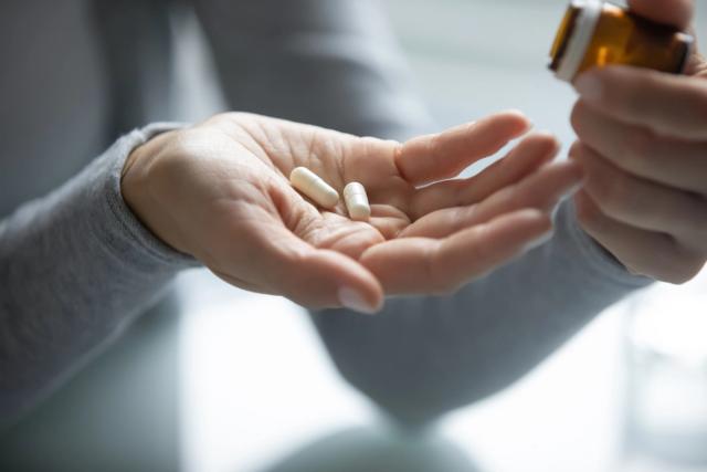 a person is pouring pills from a bottle into their hand .