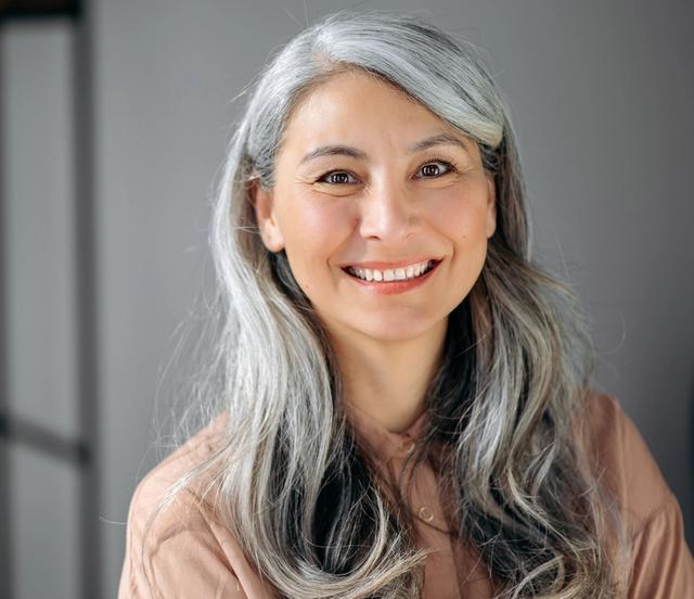 a woman with gray hair is smiling for the camera .