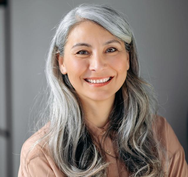 a woman with gray hair is smiling for the camera .